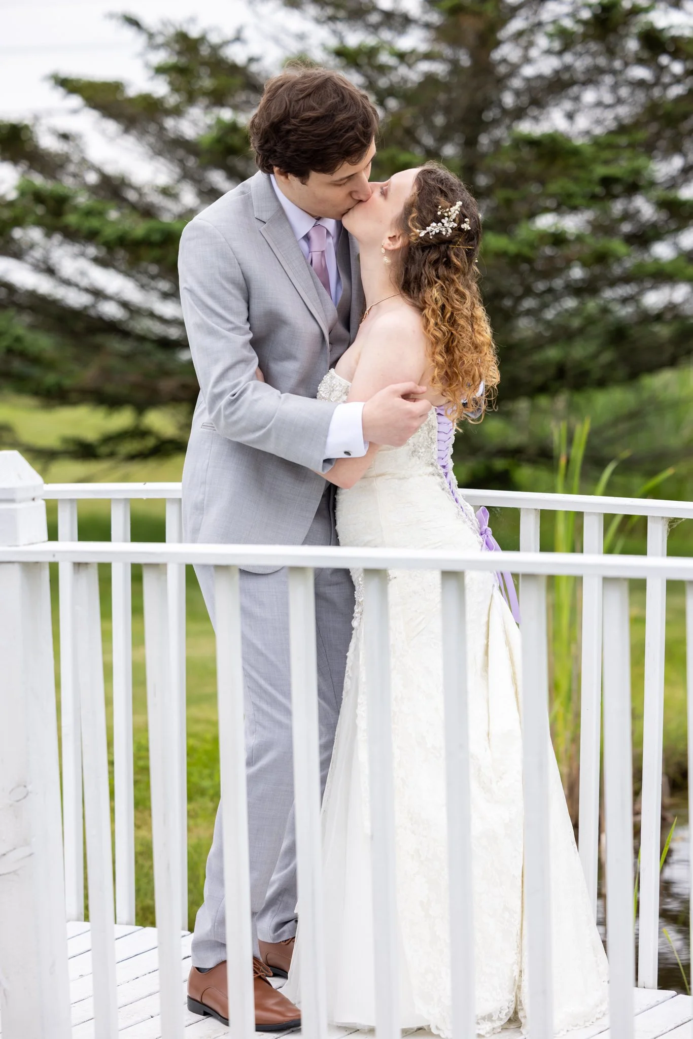 Bride and groom sharing a kiss on a white porch on their wedding day, wedding photography by David Pierre Studio