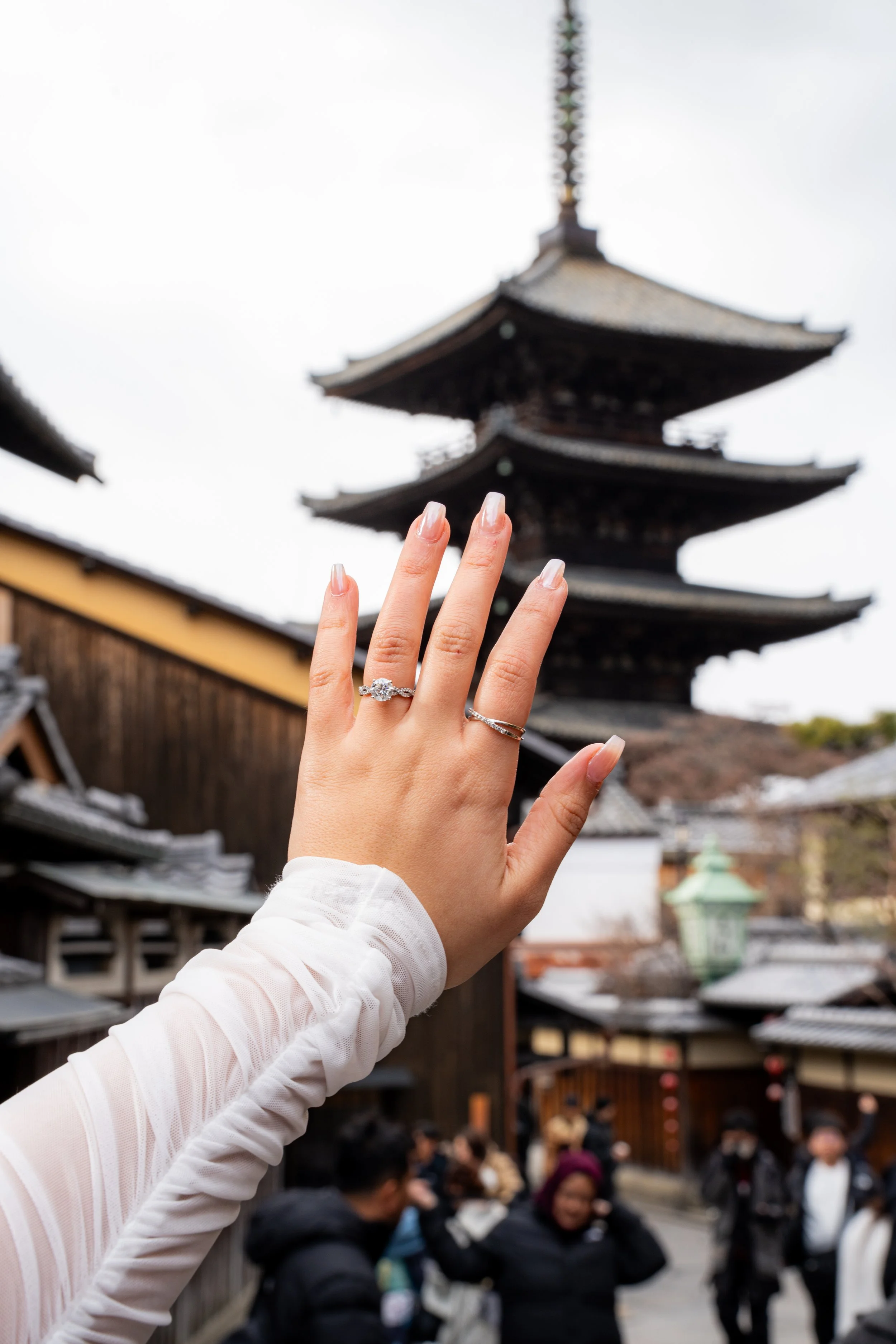 hand with an engagment ring in front of tower in kyoto Japan