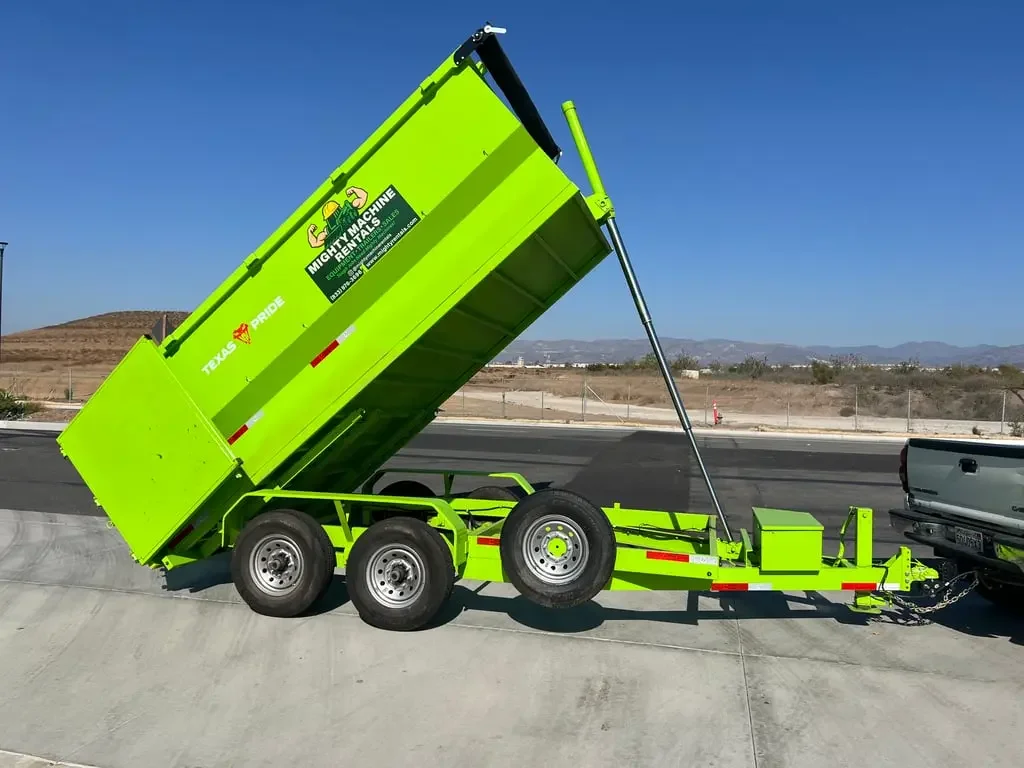 Bright green dump trailer attached to a vehicle on a roadway with desert landscape in the background. Dump trailer rentals in Santa Ana, CA