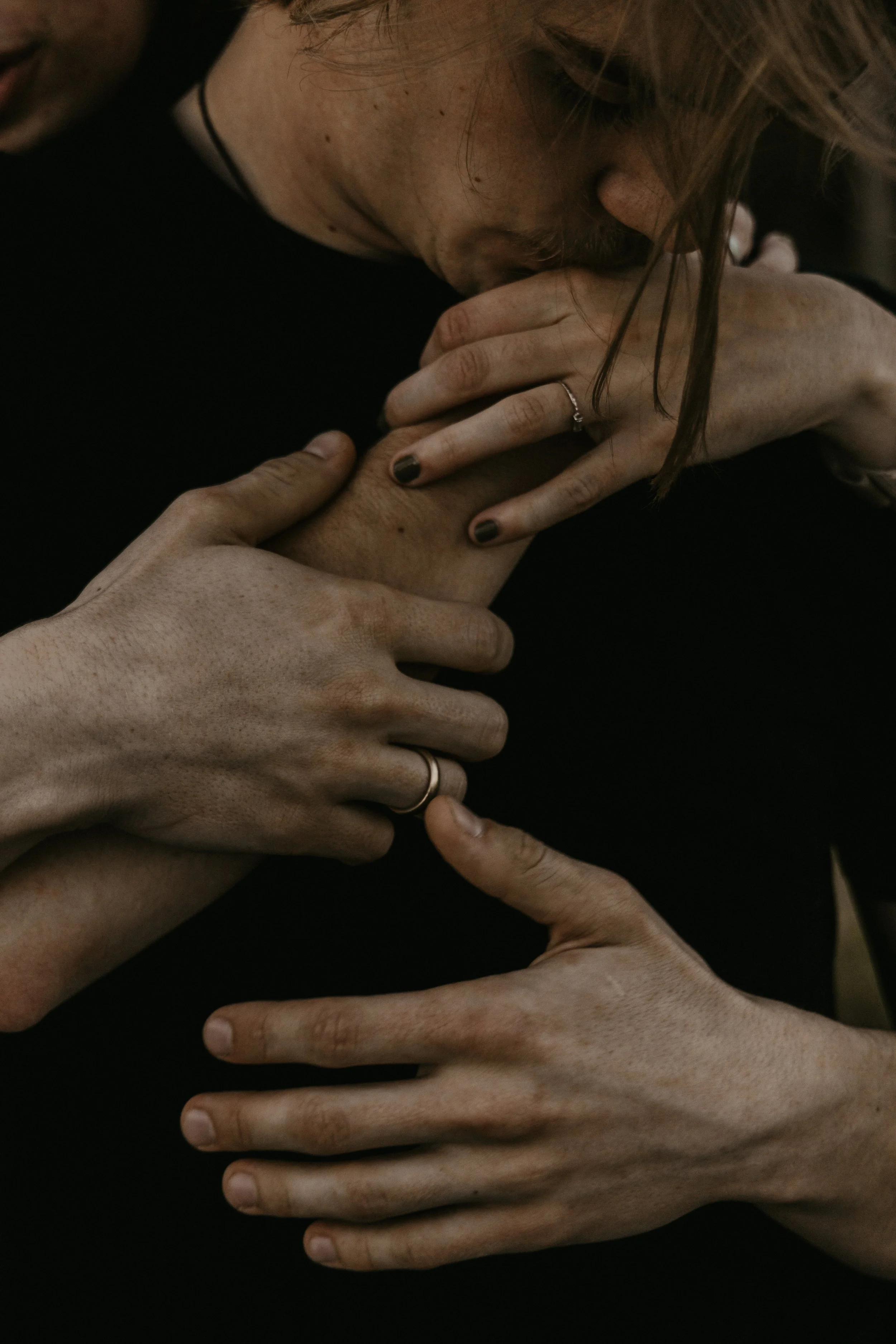 A person with freckles and light brown hair, with hands gently holding and touching her chest and neck, showing emotional intimacy or comfort.