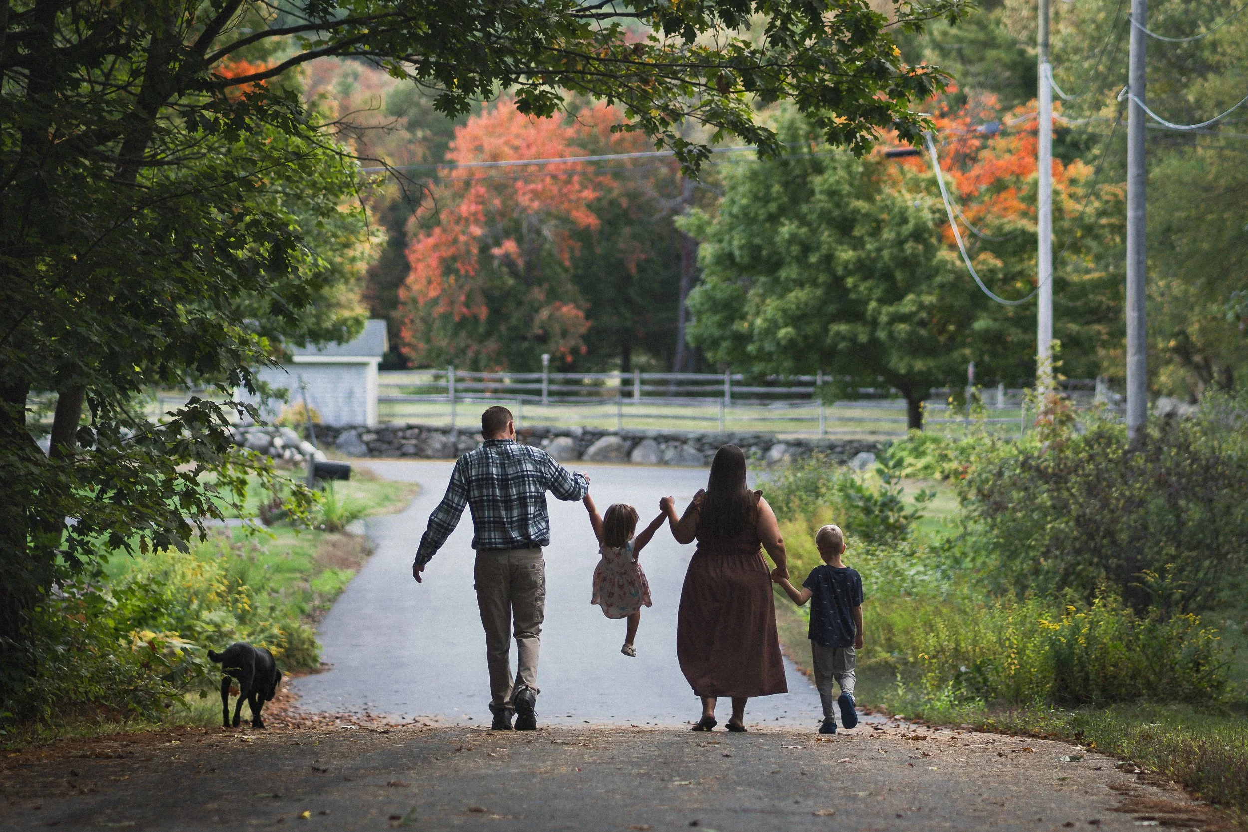 Family walking together on a quiet road during a lifestyle photography session in Central Massachusetts