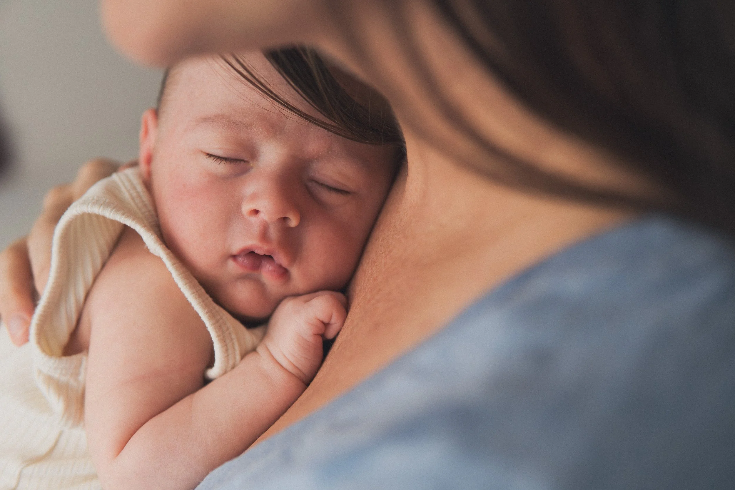 Newborn baby sleeping peacefully on a mom's chest during an in-home newborn photography session in Central Massachusetts.