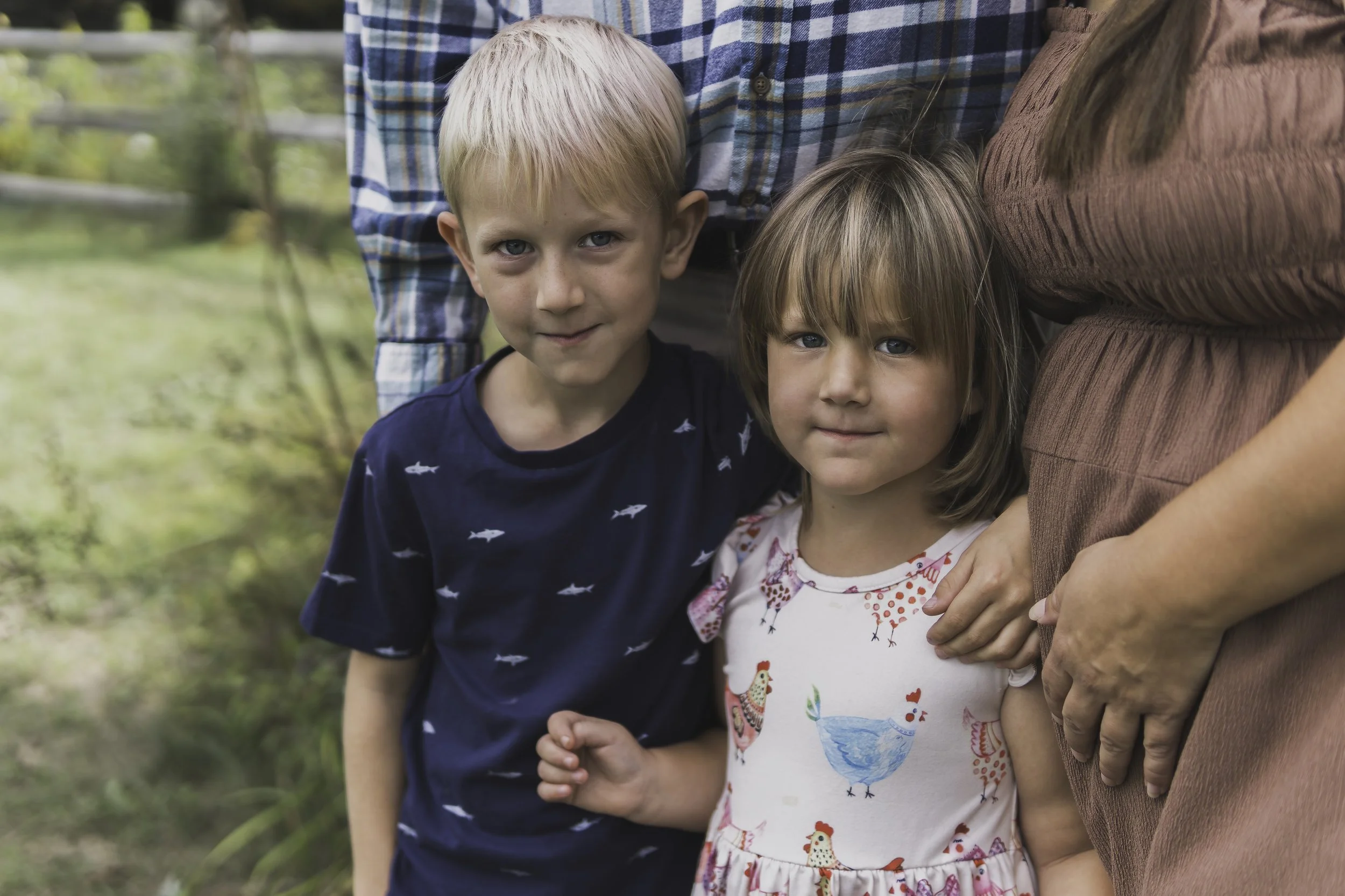Brother and sister smiling during outdoor family portrait session in Central Massachusetts with warm natural light.
