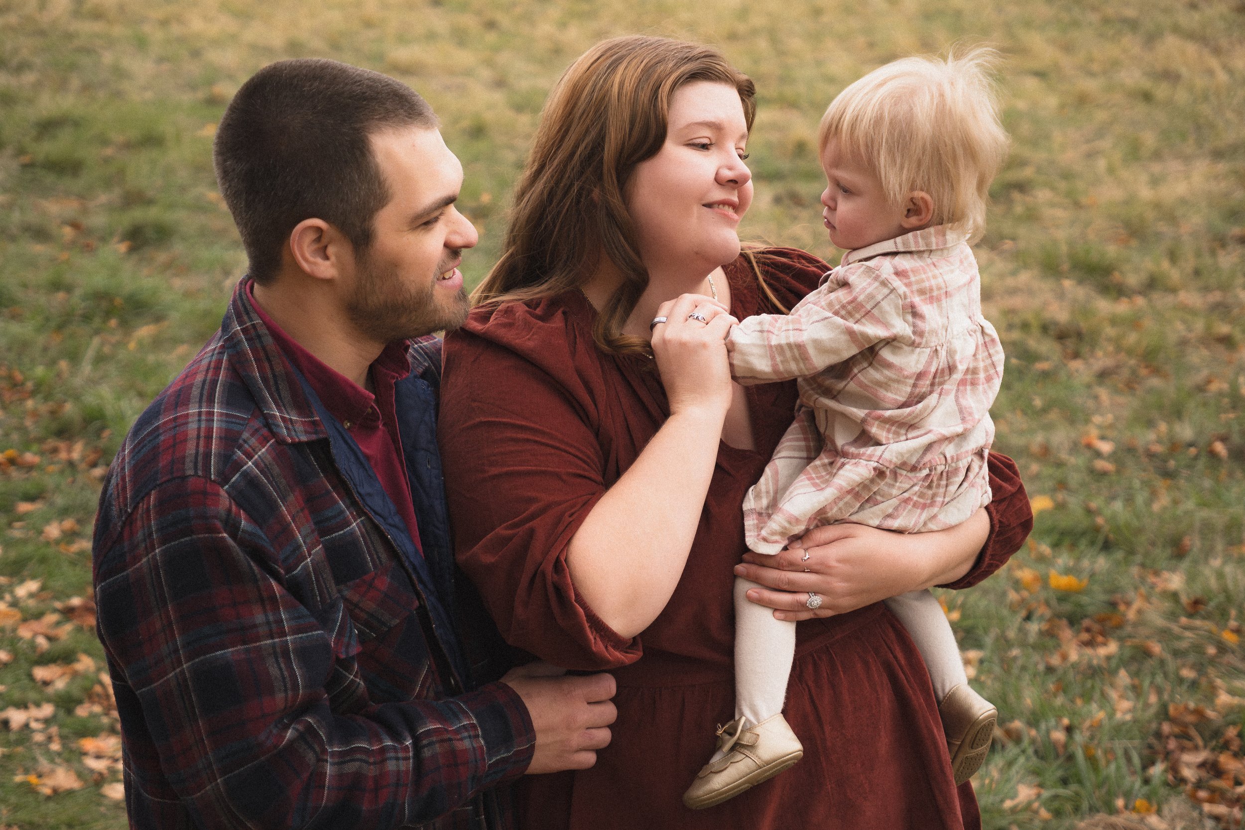 Parents holding their toddler during an outdoor lifestyle family photography session in Concord Massachusetts.