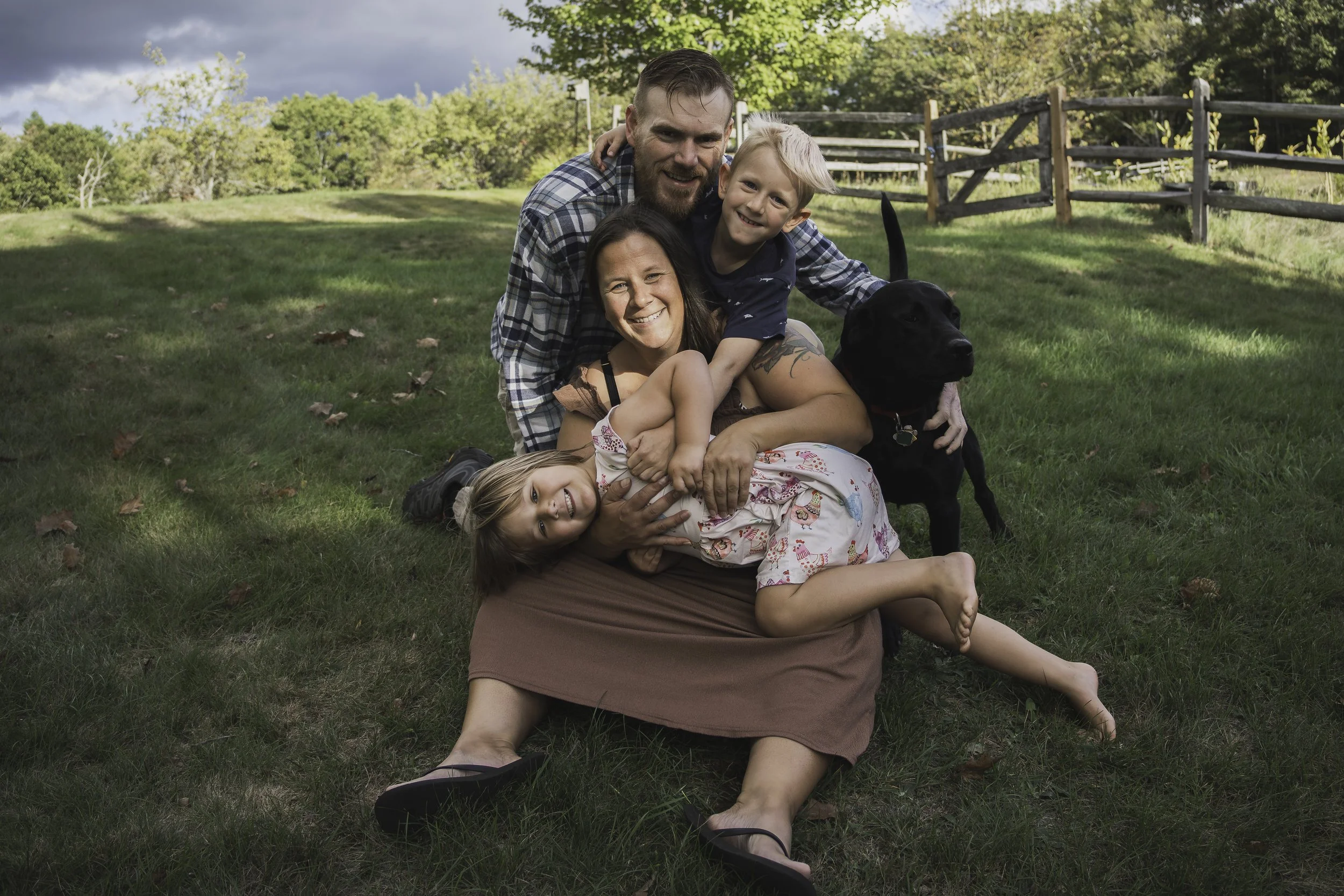 Parents cuddling with two young children during sunset family session in open field near Westminster Massachusetts