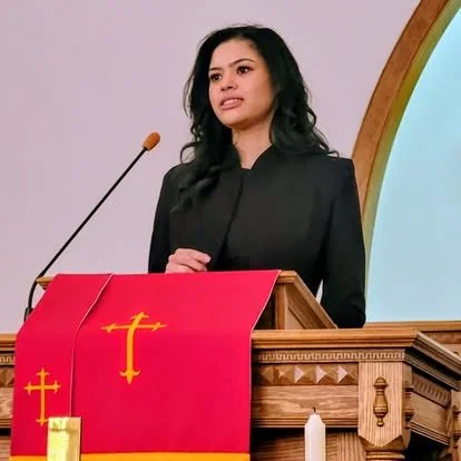 A woman standing at a church pulpit, speaking or giving a sermon.