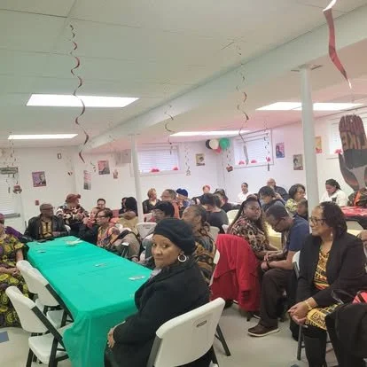 People sitting at tables in a decorated indoor party room.