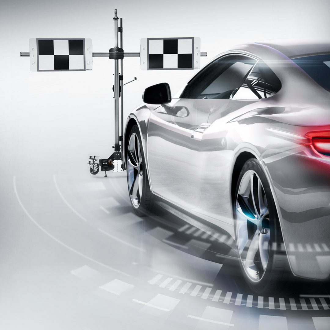 A silver sports car undergoing autonomous vehicle testing with a calibration or sensor setup, including a stereo camera and checkerboard targets for calibration.