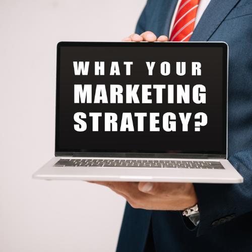 Person in suit holding a laptop that displays the text "What your marketing strategy?"