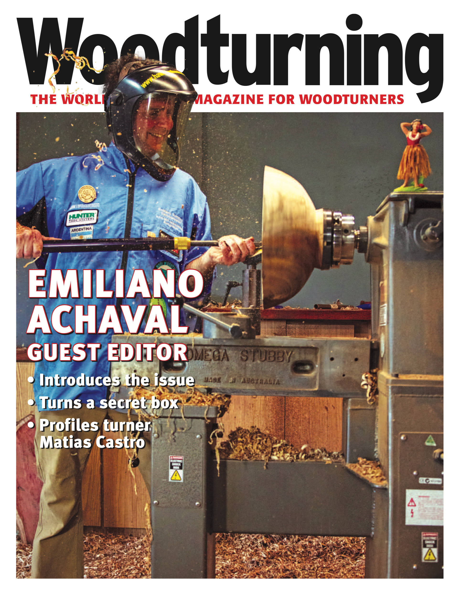 Cover of Woodturing magazine featuring Emiliano Achaval using a wood lathe to turn wood, with a small hula girl figurine on the machine and wood shavings around.