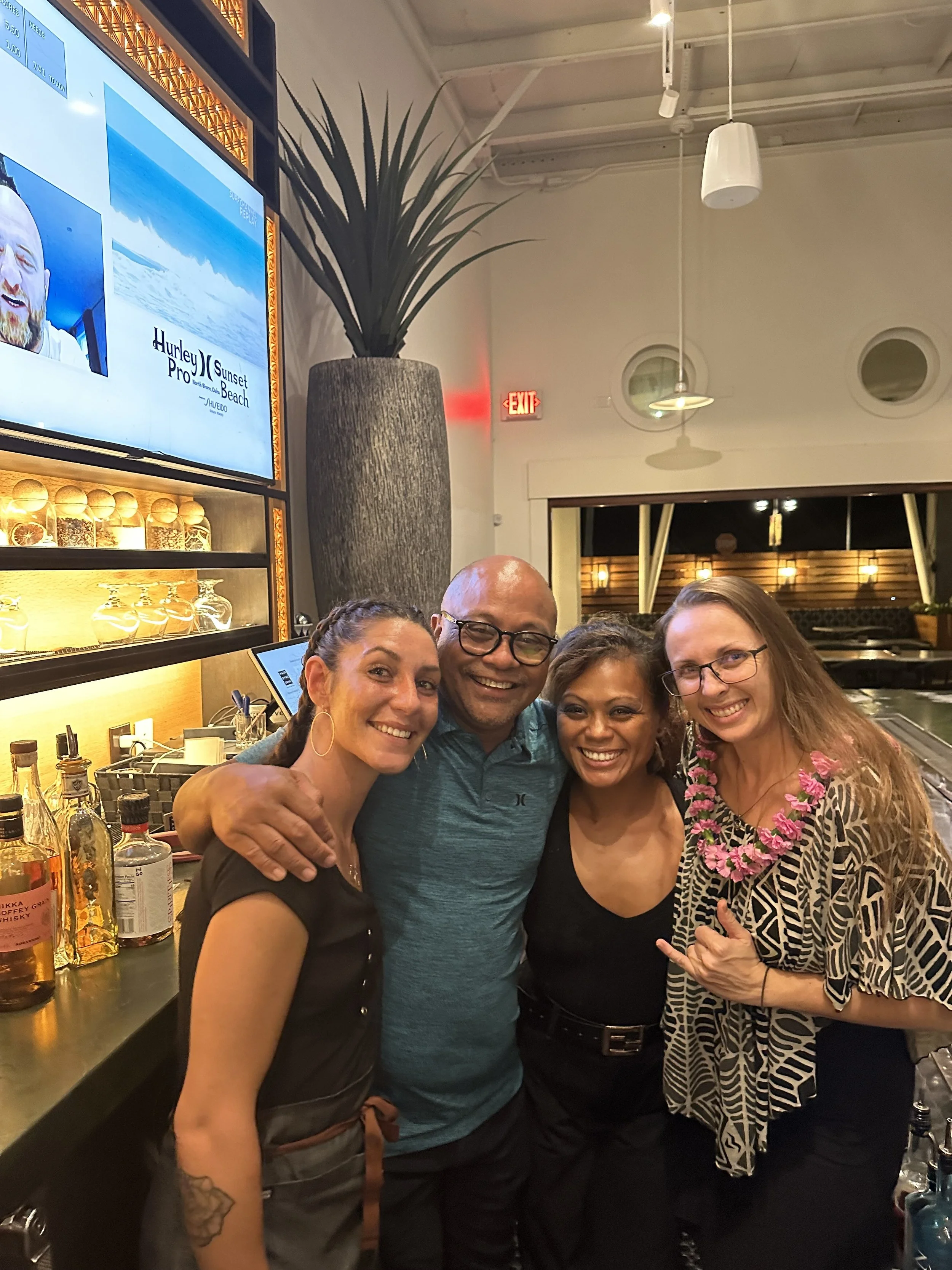 Jackie (right) stands behind the bar smiling at the camera beside Emma Ko'omoa, Joey Macadangdang, and Donna Esteban.