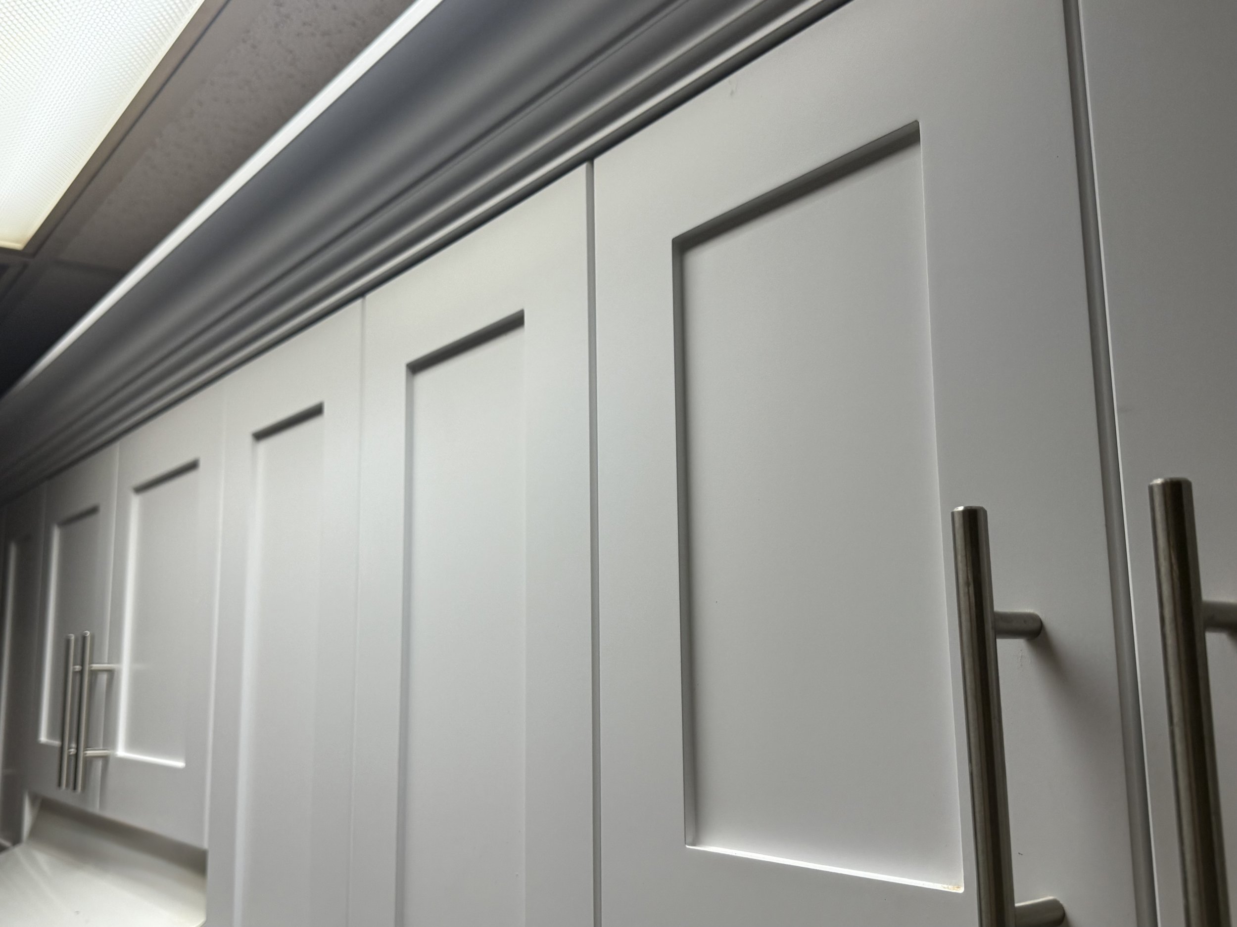 Close-up of white kitchen cabinets with metallic door handles.