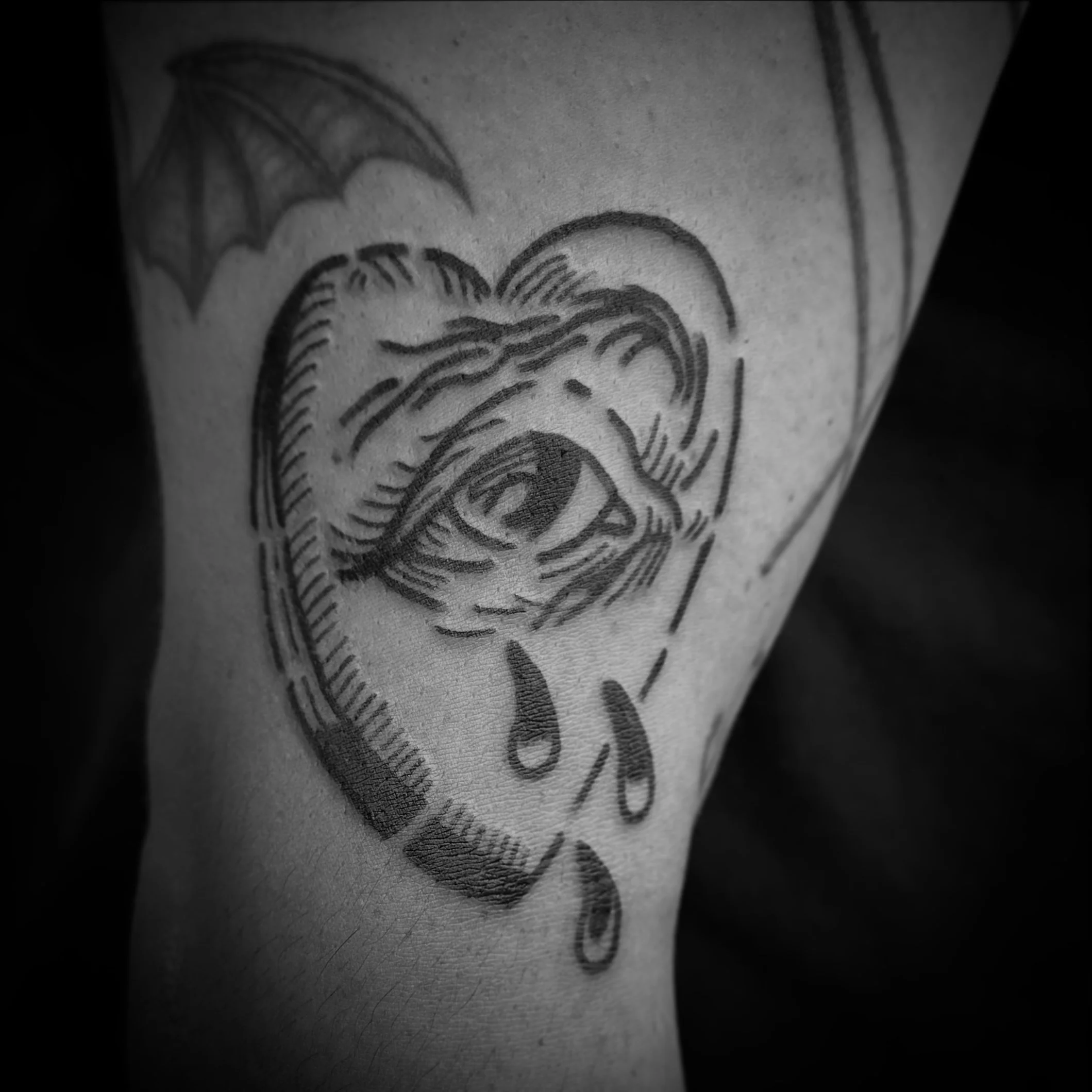 Black ink tattoo of a weeping Ouija board planchette.