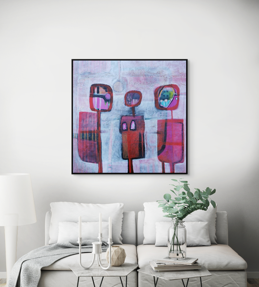 Abstract artwork hanging above a white sofa with white cushions, a coffee table with candles, a vase with greenery, and a gray blanket in a modern living room.