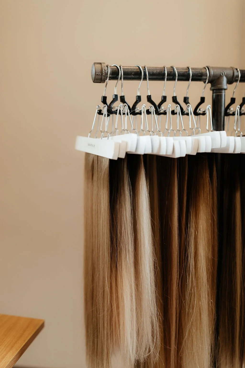 Clothing display with hair extensions on hangers and foam inserts, set against a beige wall.