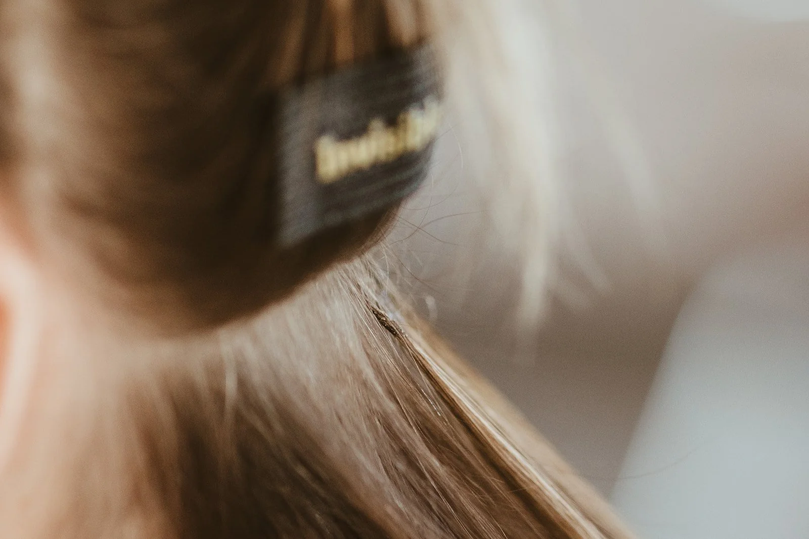 Close-up of a person with a black hair clip holding their straight, light brown hair, focusing on the hair and clip.