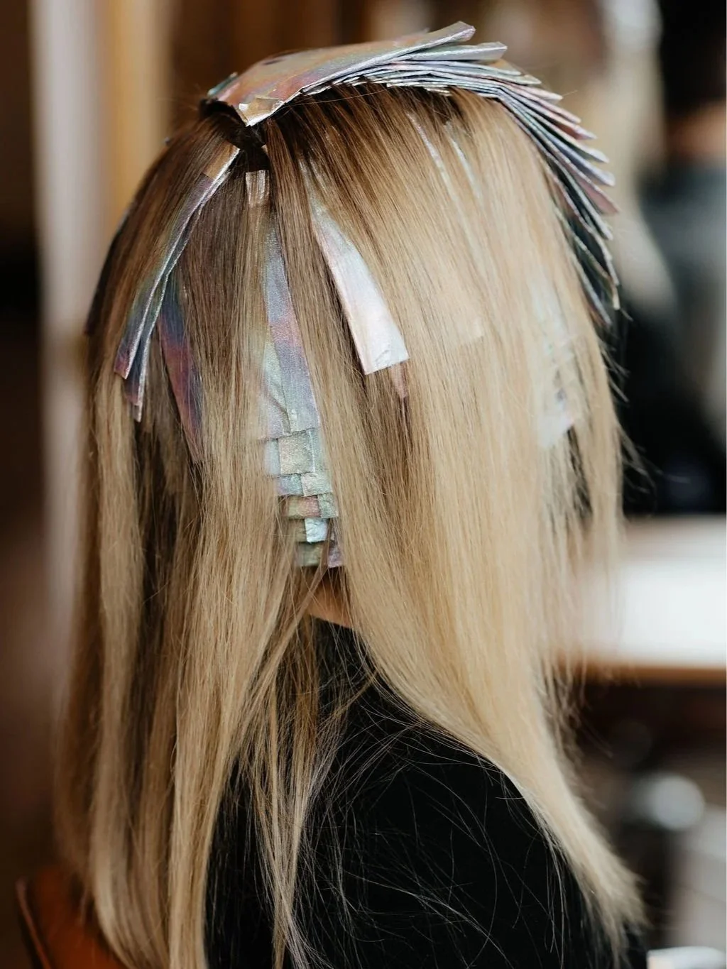 Hair styled with bleached blonde color and layered with iridescent foil highlights.