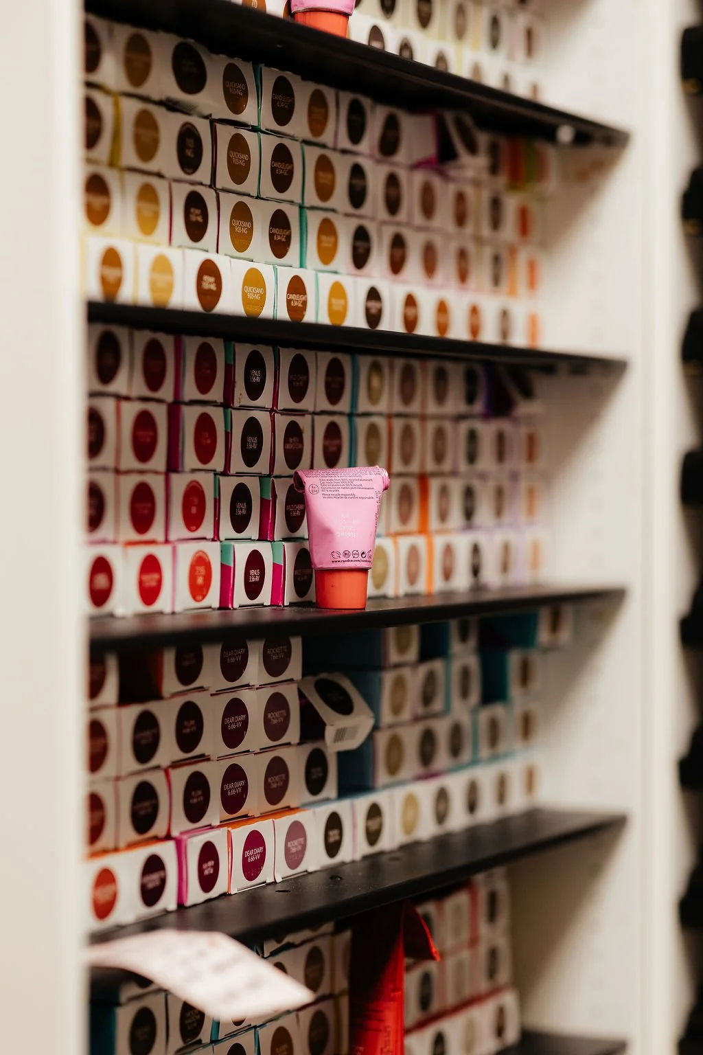 Shelf stocked with multiple boxes of skincare products, with one pink tube in the center.