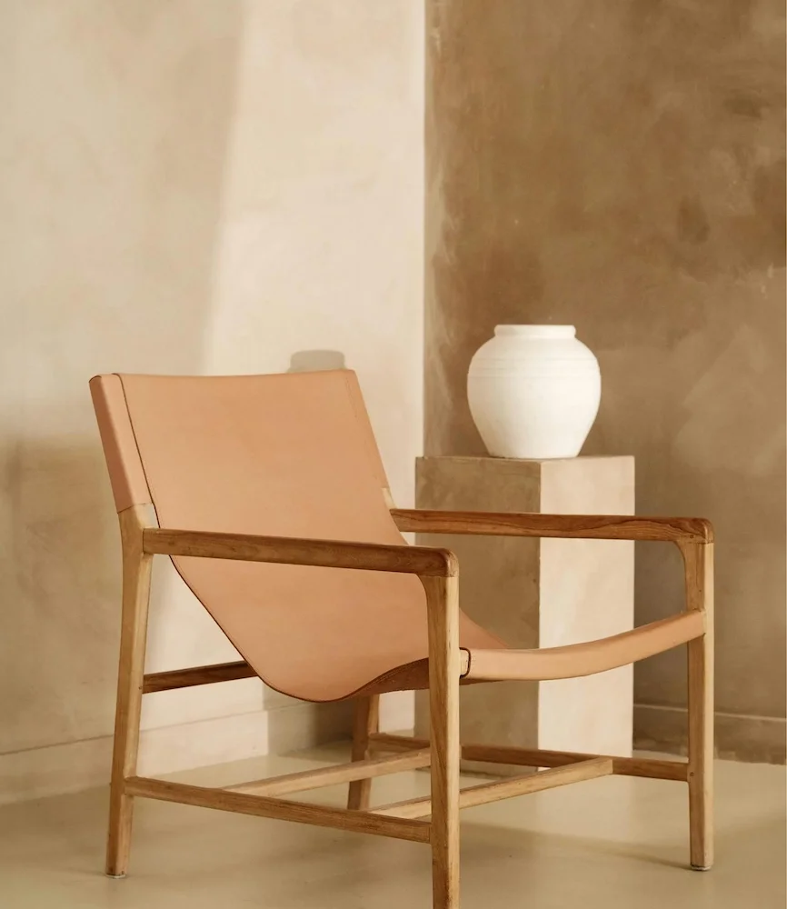 Bespoke consultation vignette with a leather and wood chair against a natural, hand-applied plaster wall texture.