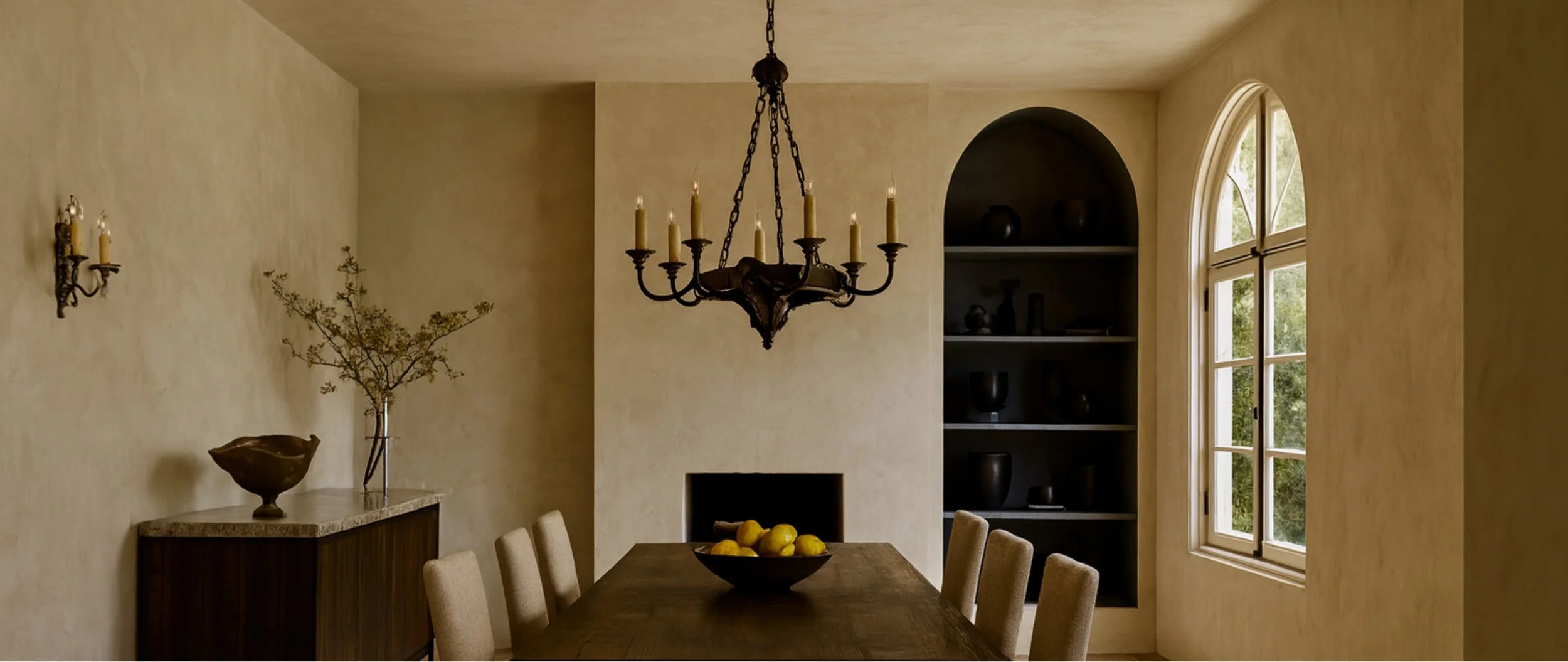 Luxury dining room in Los Angeles featuring a hand-applied Marmorino plaster finish, arched window, and antique black iron chandelier.