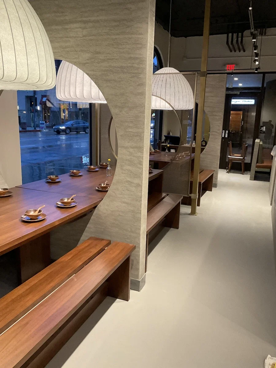 Modern dining room at Sichuan Impression restaurant in Alhambra featuring multiple circular moon gate partitions finished in grey textured Venetian plaster.