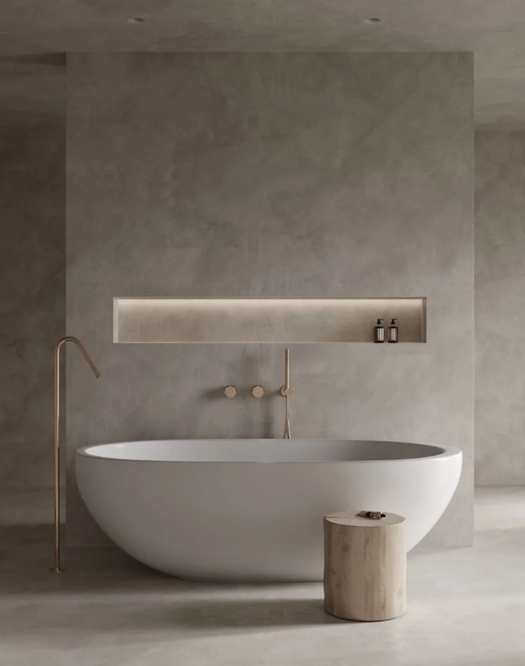 A minimalist luxury bathroom featuring a white freestanding soaking tub against seamless grey waterproof Venetian plaster walls and floors, highlighted by a recessed niche with warm integrated lighting and elegant gold fixtures.