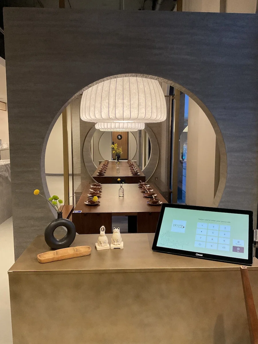 Dark grey textured Venetian plaster finish on a circular moon gate archway in the Sichuan Impression Alhambra restaurant entry.