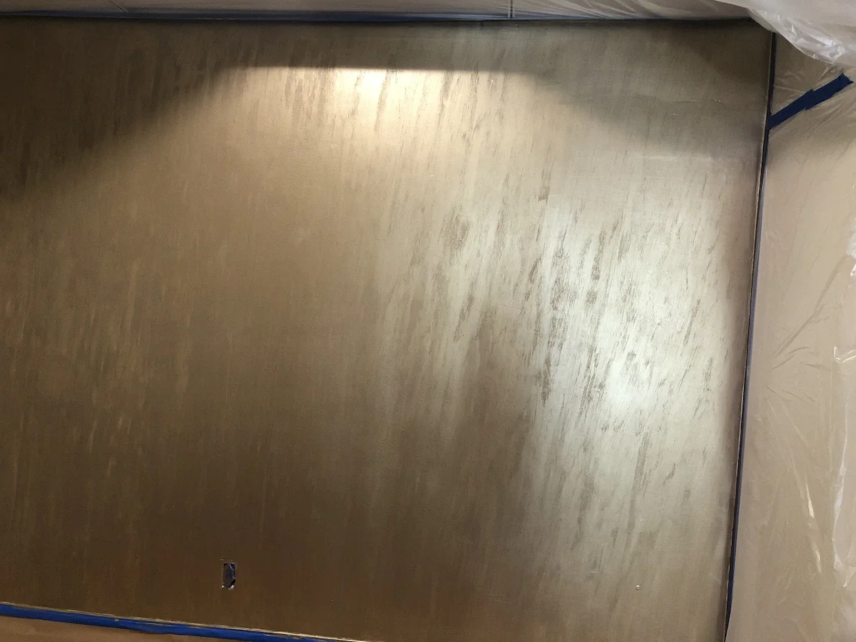 Detail of a champagne gold metallic Venetian plaster wall finish with a vertical textured application at Esencia Salon and Spa.