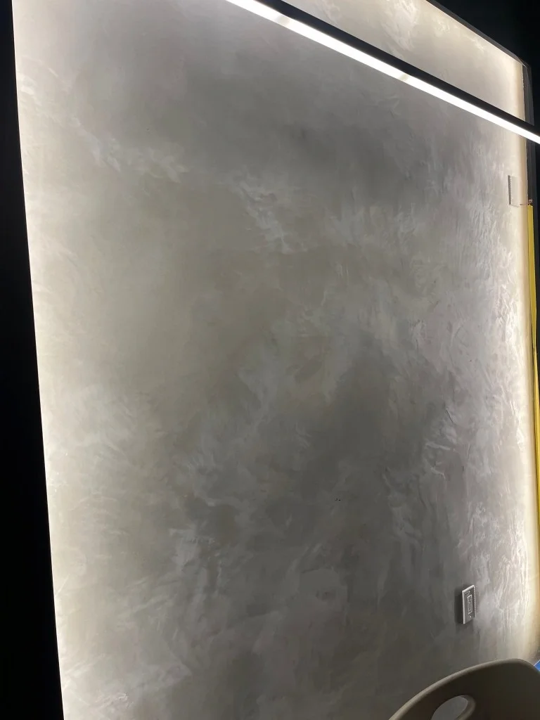Polished concrete Venetian plaster wall with a hand-troweled finish, illuminated by an integrated LED strip light.