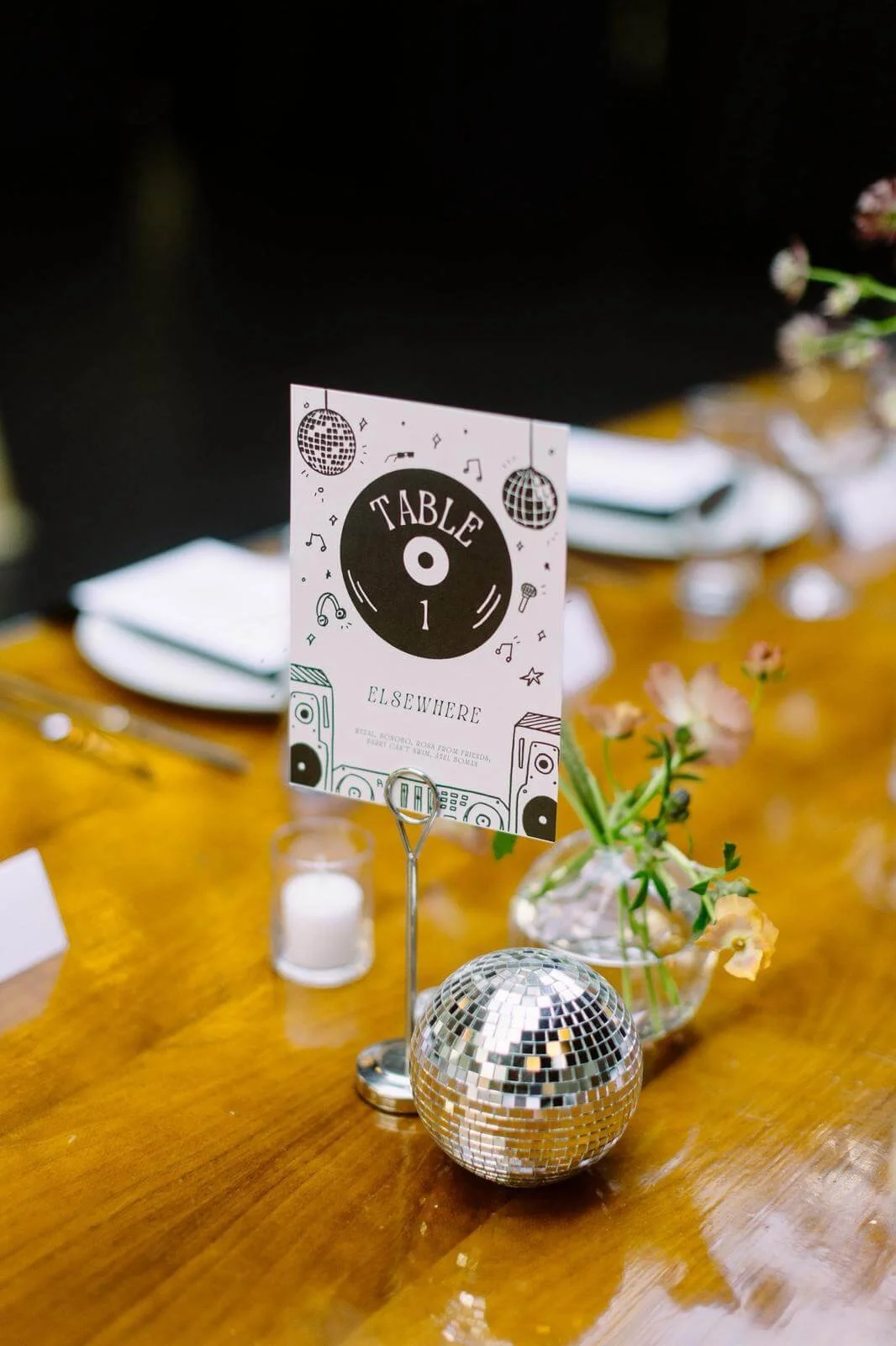 Illustrated paper table sign by Carolyn Yoo displayed beside a small disco ball.