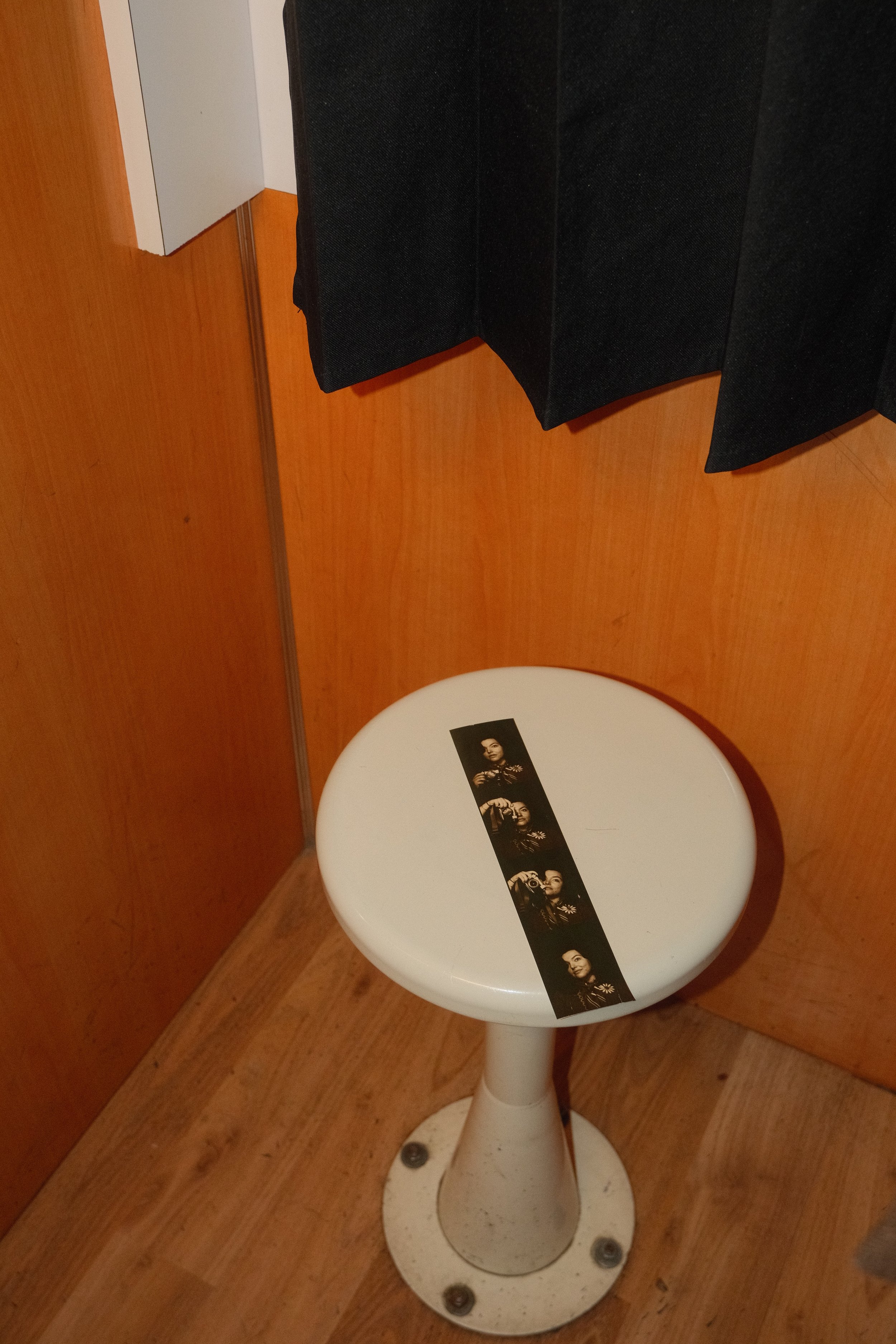 A white round stool with a strip of four black-and-white photographs placed vertically on top.