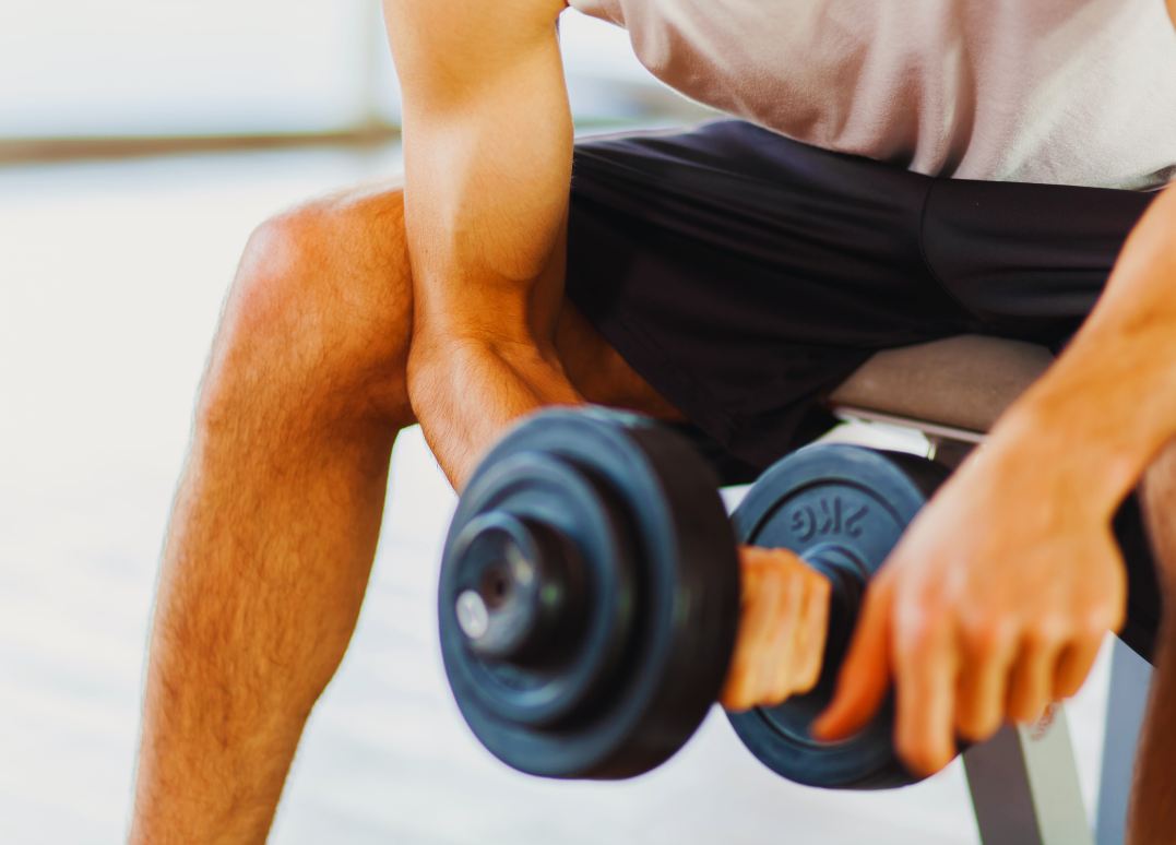 A person exercising with a dumbbell in a gym setting.
