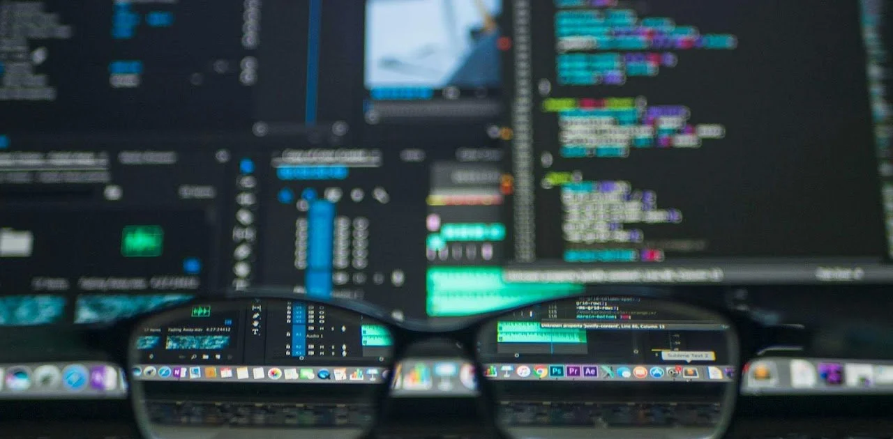 Computer monitor displaying video editing software with glasses reflecting the screen.