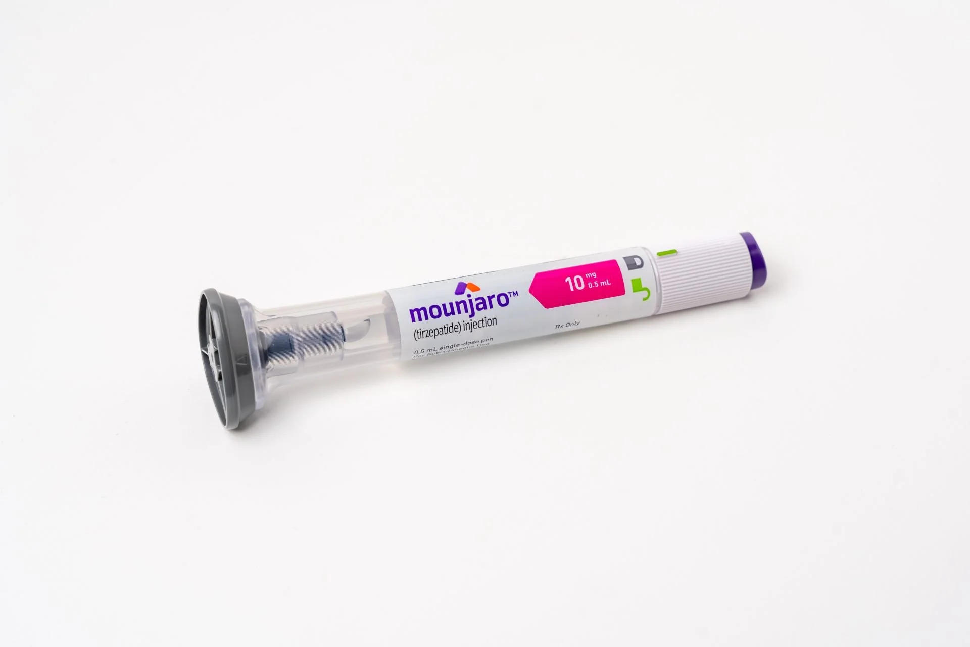 A syringe labeled 'Mounjaro' with purple and pink markings, lying on a white surface.
