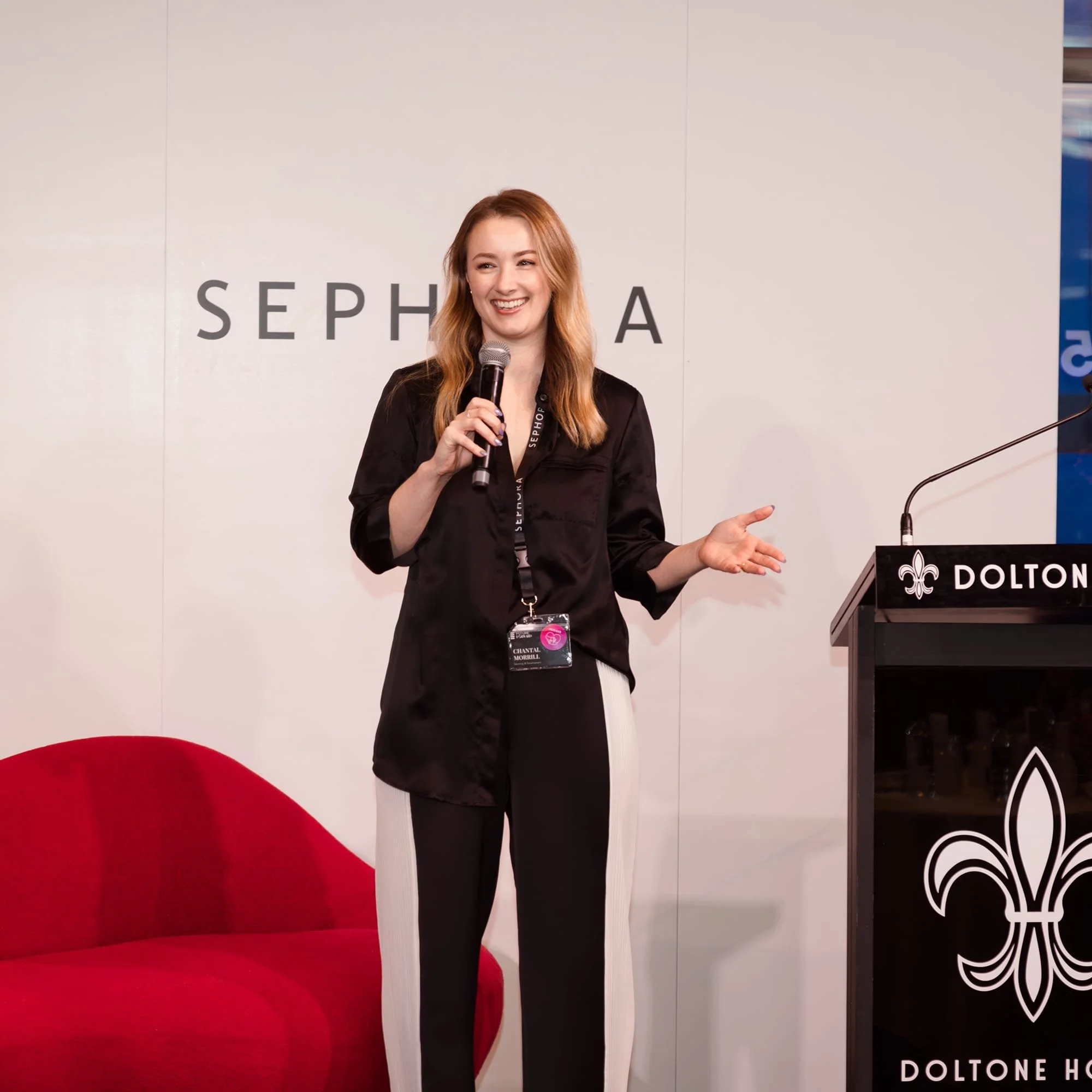 Keynote speaker delivering a conference presentation on communication and leadership, speaking on stage with a microphone at a corporate event