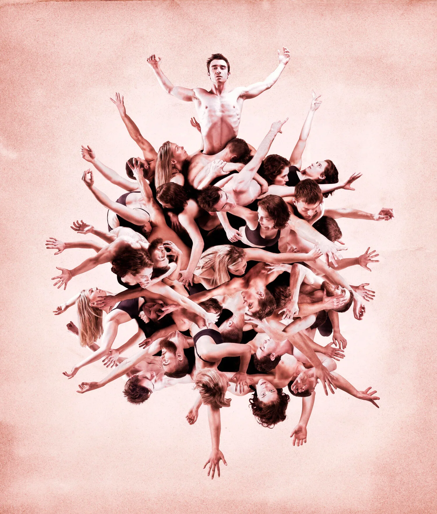 Group of intertwined nude and dressed dancers forming a human sculpture with a man standing at the top, against a pink background.