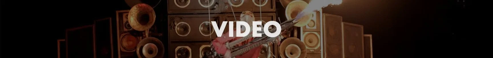 Overhead view of a person with a guitar surrounded by multiple speakers and musical equipment in a music studio.