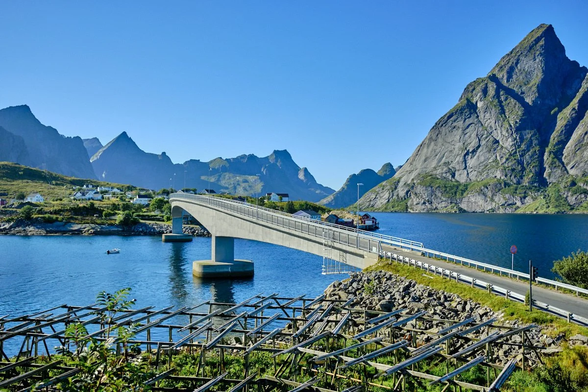 Scenic view of a bridge over a fjord with mountains in the background and small houses nearby, in Norway.