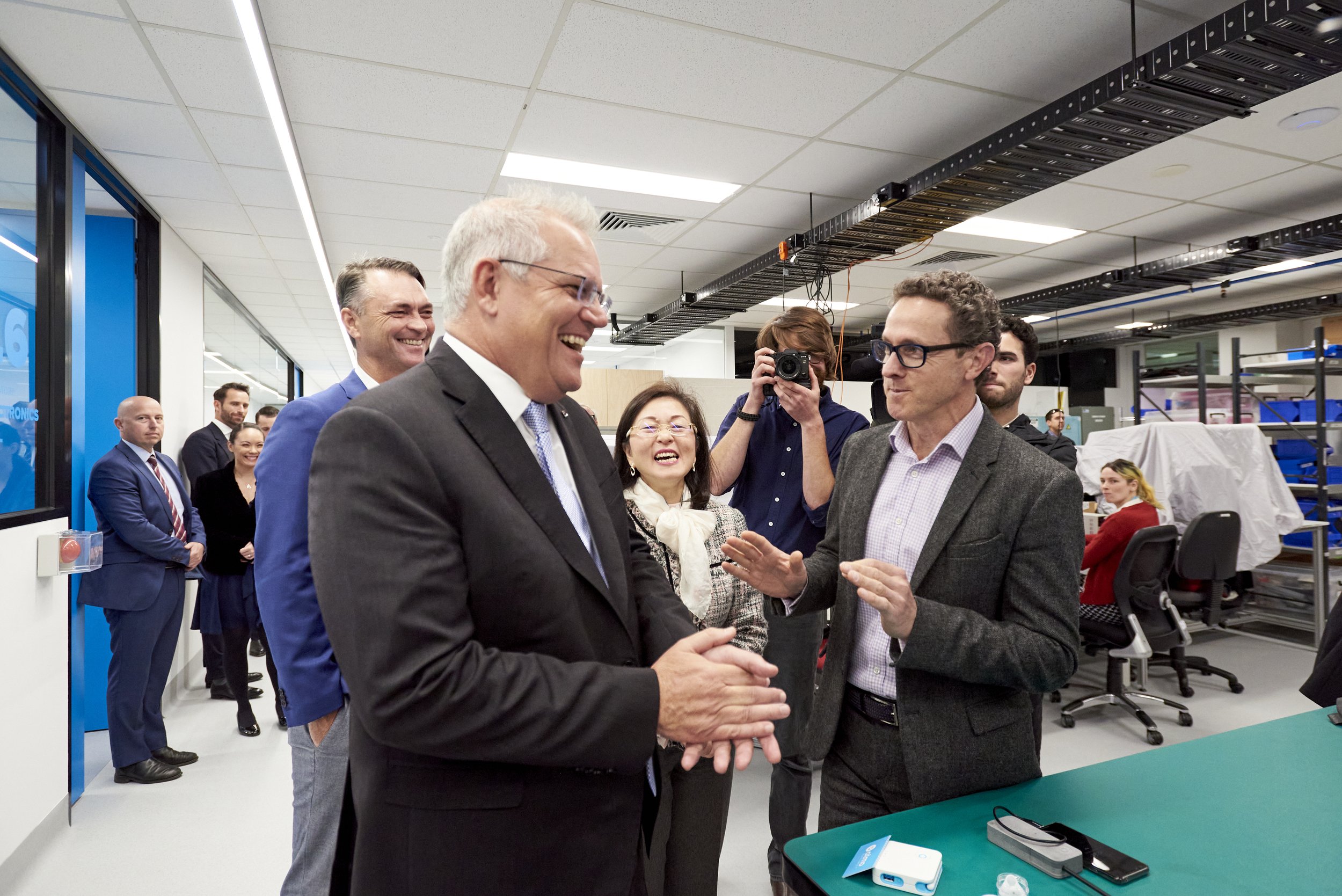 Group of professionals in a modern office setting, engaging in conversation and smiling.