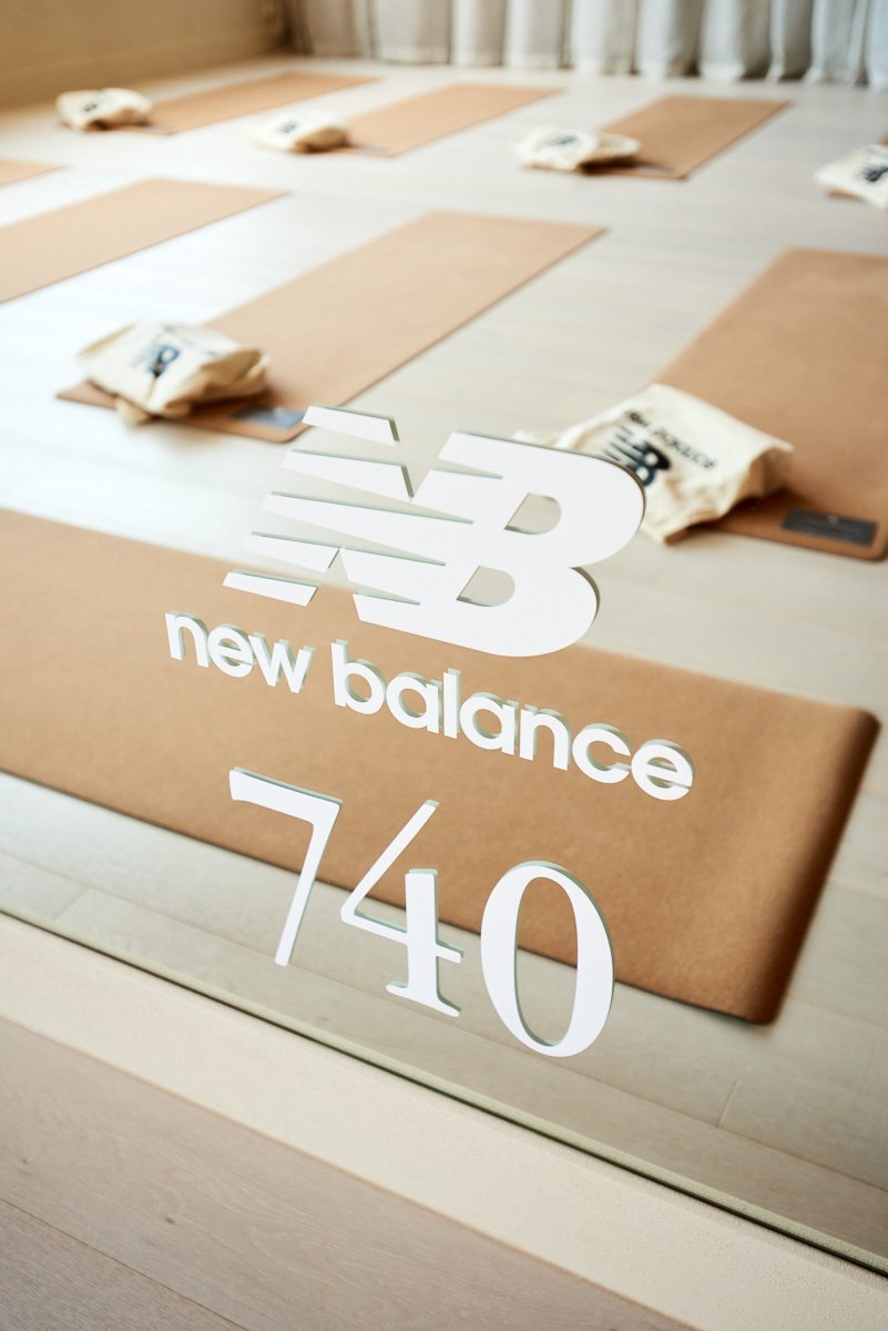 Mirror reflecting a yoga studio with yoga mats and tote bags on the floor. There is a New Balance logo and the number 740 written on the mirror.