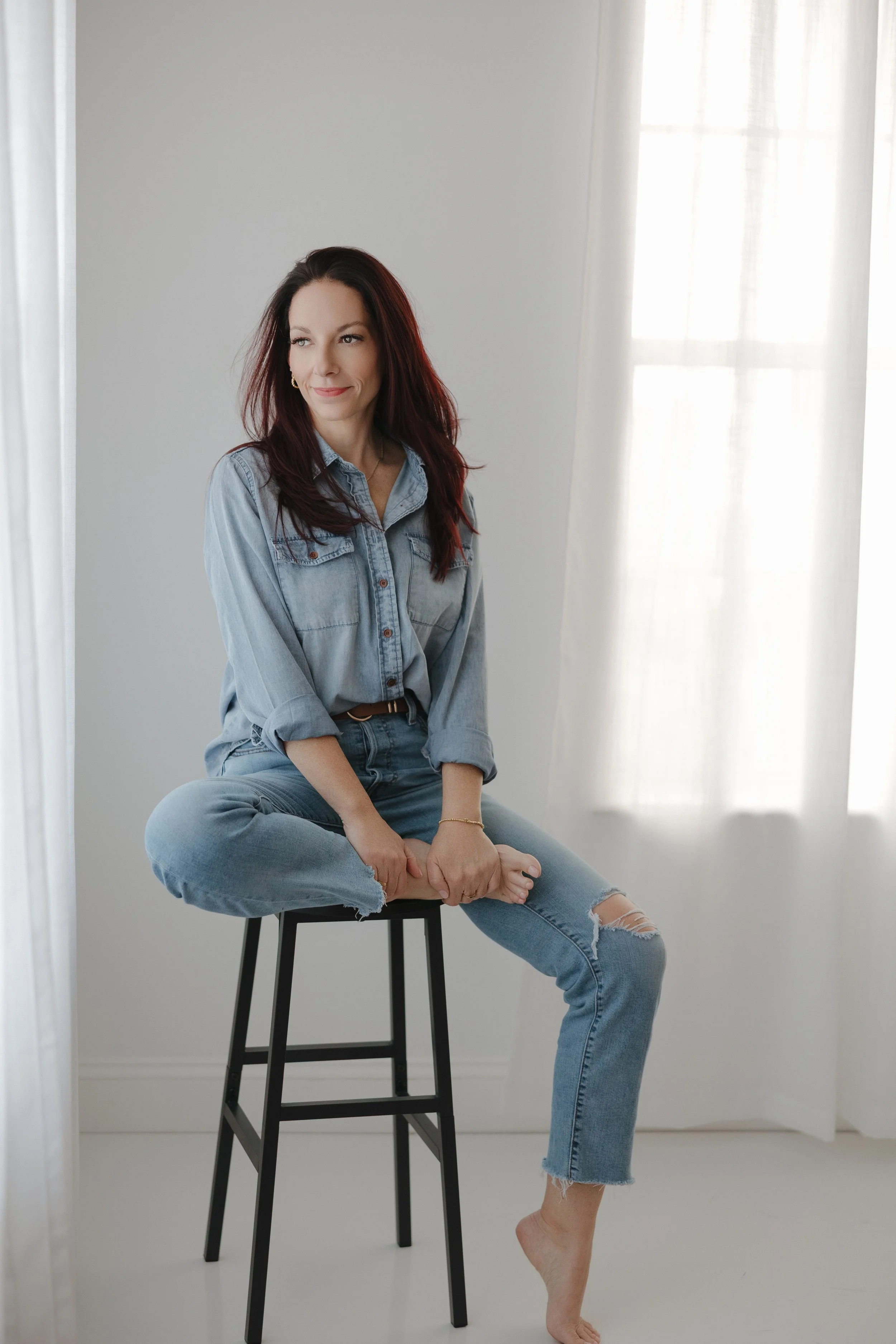konmari tidying consultant wearing jeans sitting on a stool facing a window