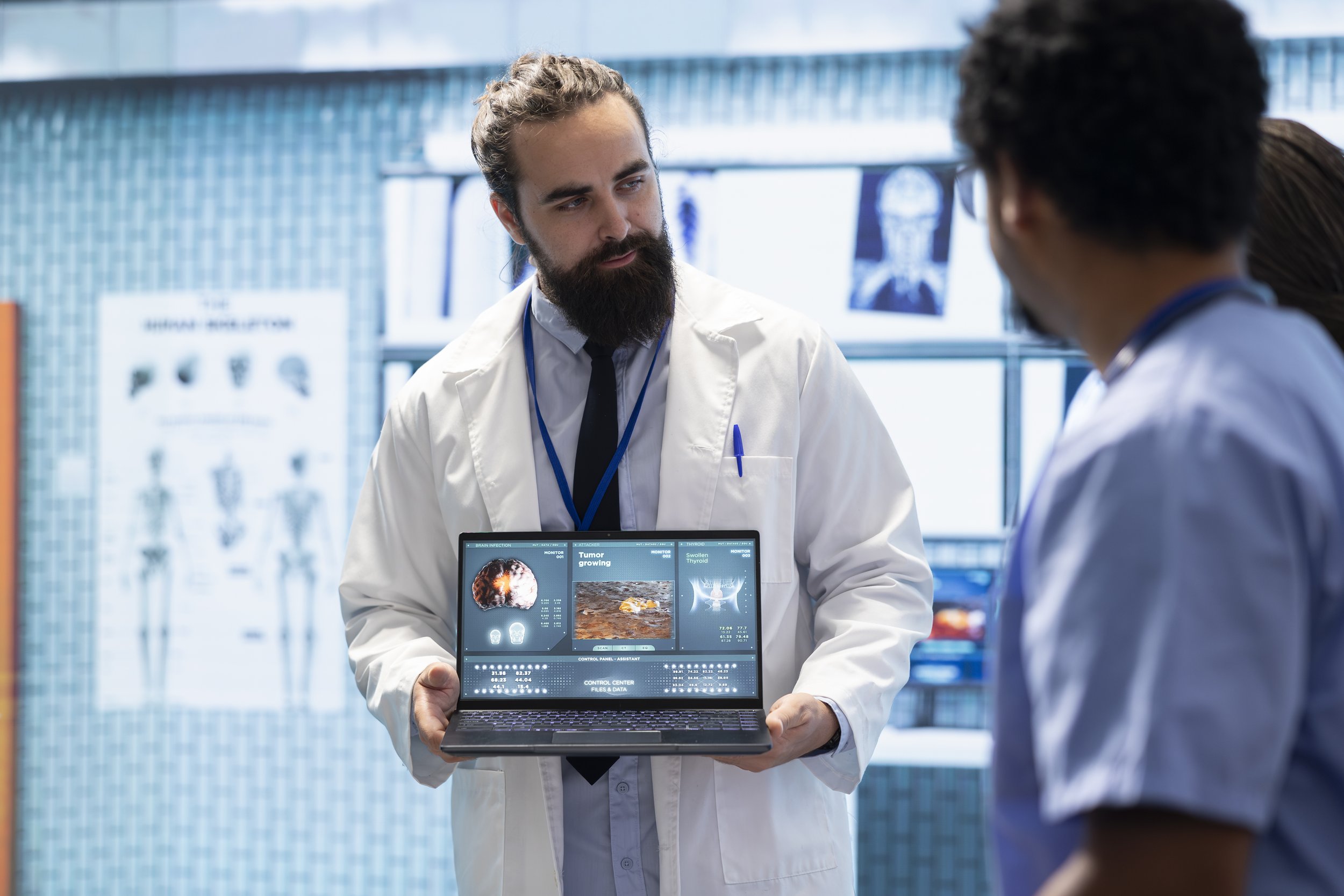 A doctor showing a laptop with medical scans to a group of colleagues in a hospital setting.