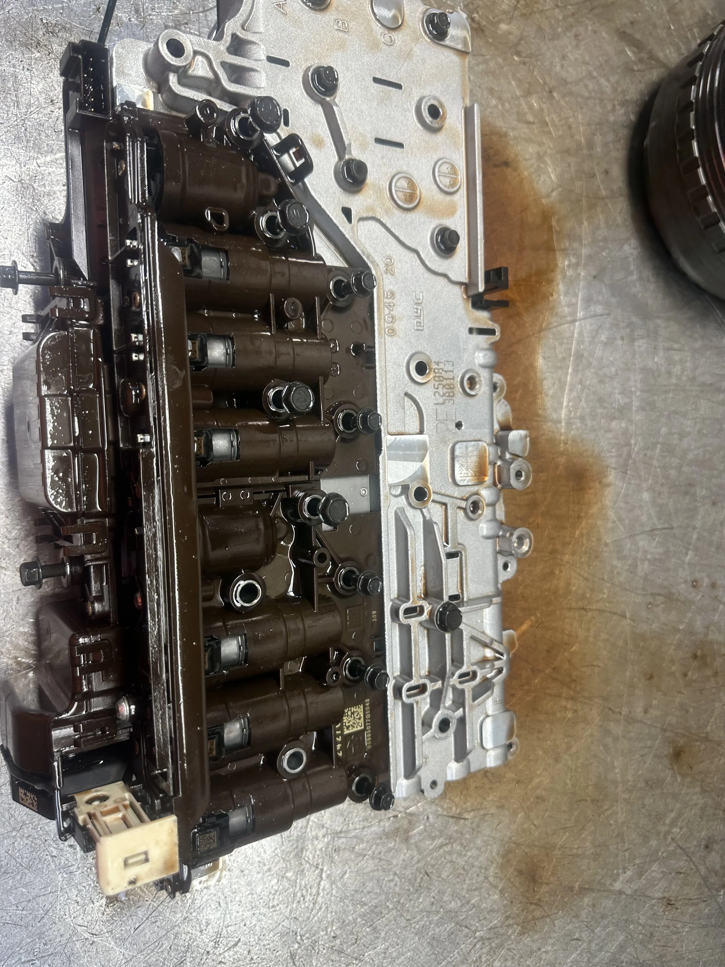 Automotive engine transmission component with black cylinders and metal casing on a metallic surface.