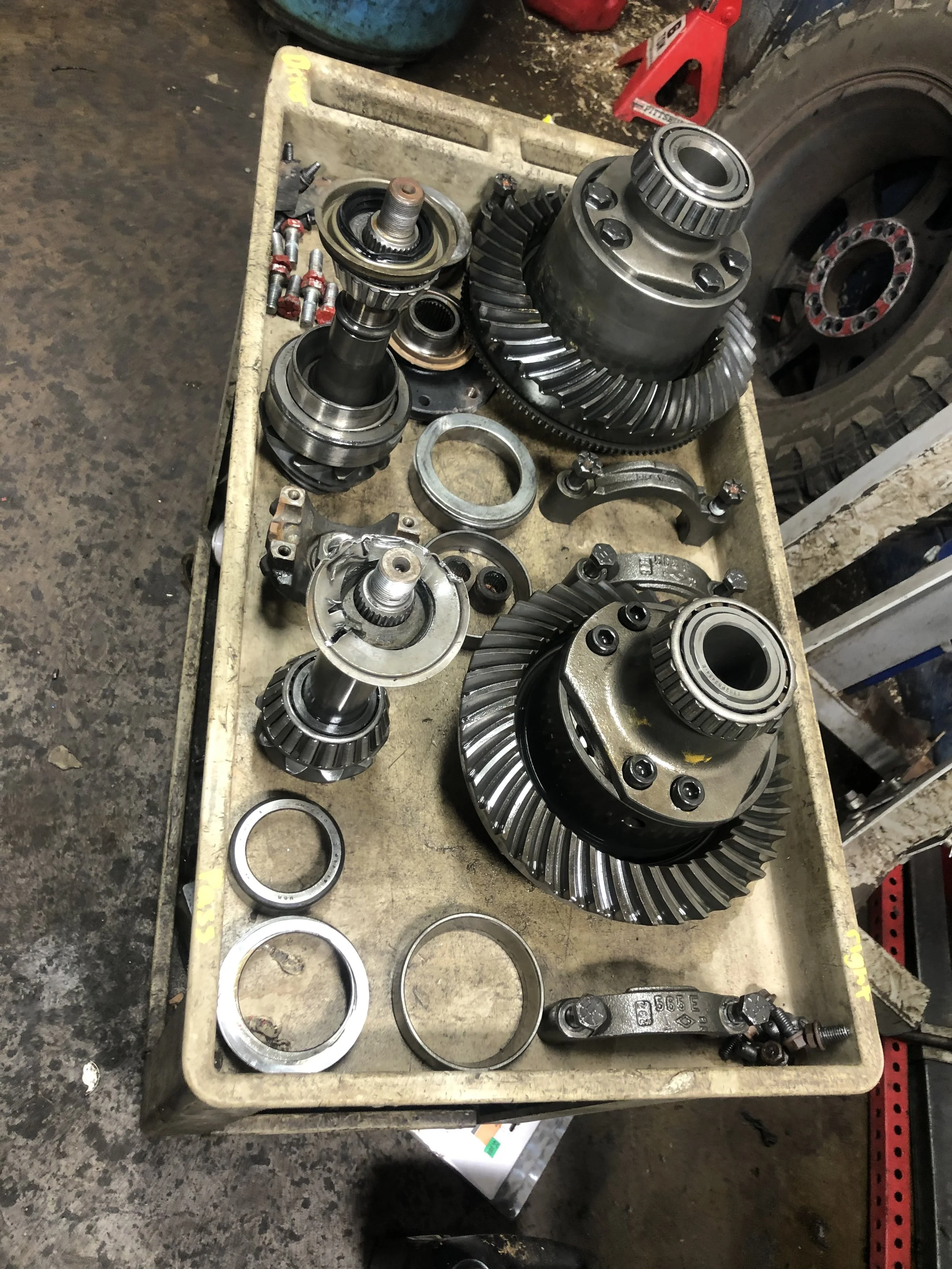 A workbench with various automotive differential parts, including gears, bearings, and shafts.