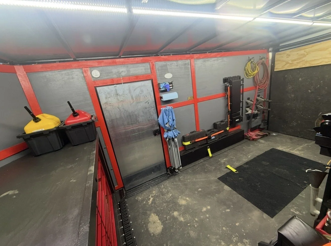 A well-organized garage with storage shelves, cleaning supplies, and gym equipment on the walls and floor.