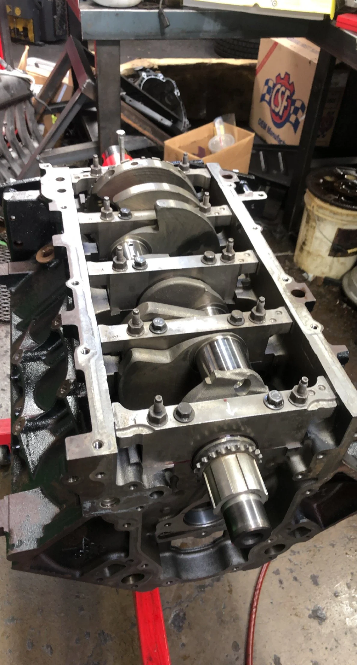 Internal view of a disassembled multi-cylinder engine block with pistons and crankshaft in a workshop.