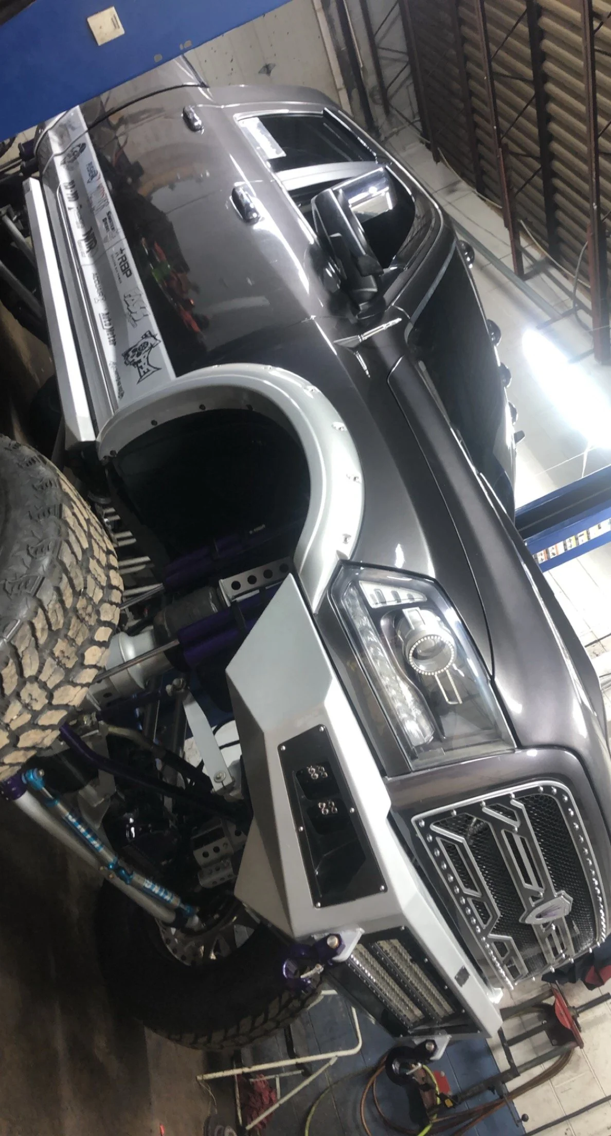 A race car with a black body and white front, equipped with a large tire and advanced suspension, inside a garage.