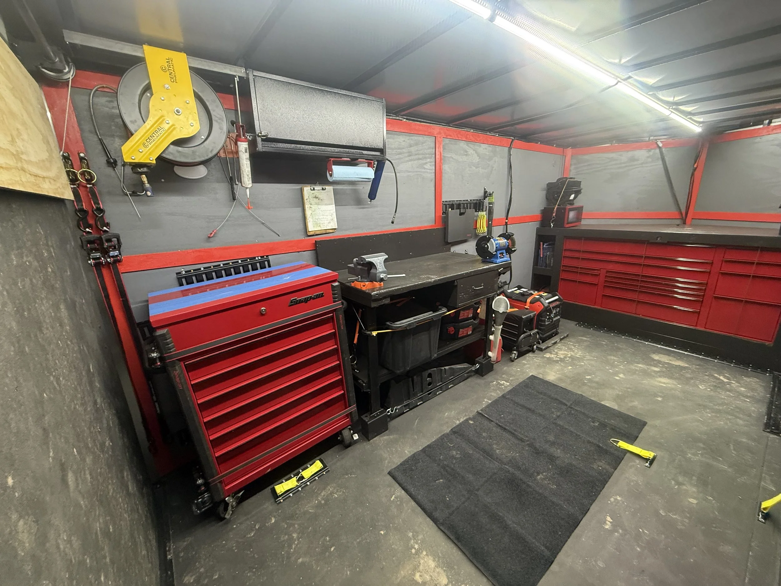 Organized garage workshop with red tool chest, black workbench, and various tools stored on the wall.