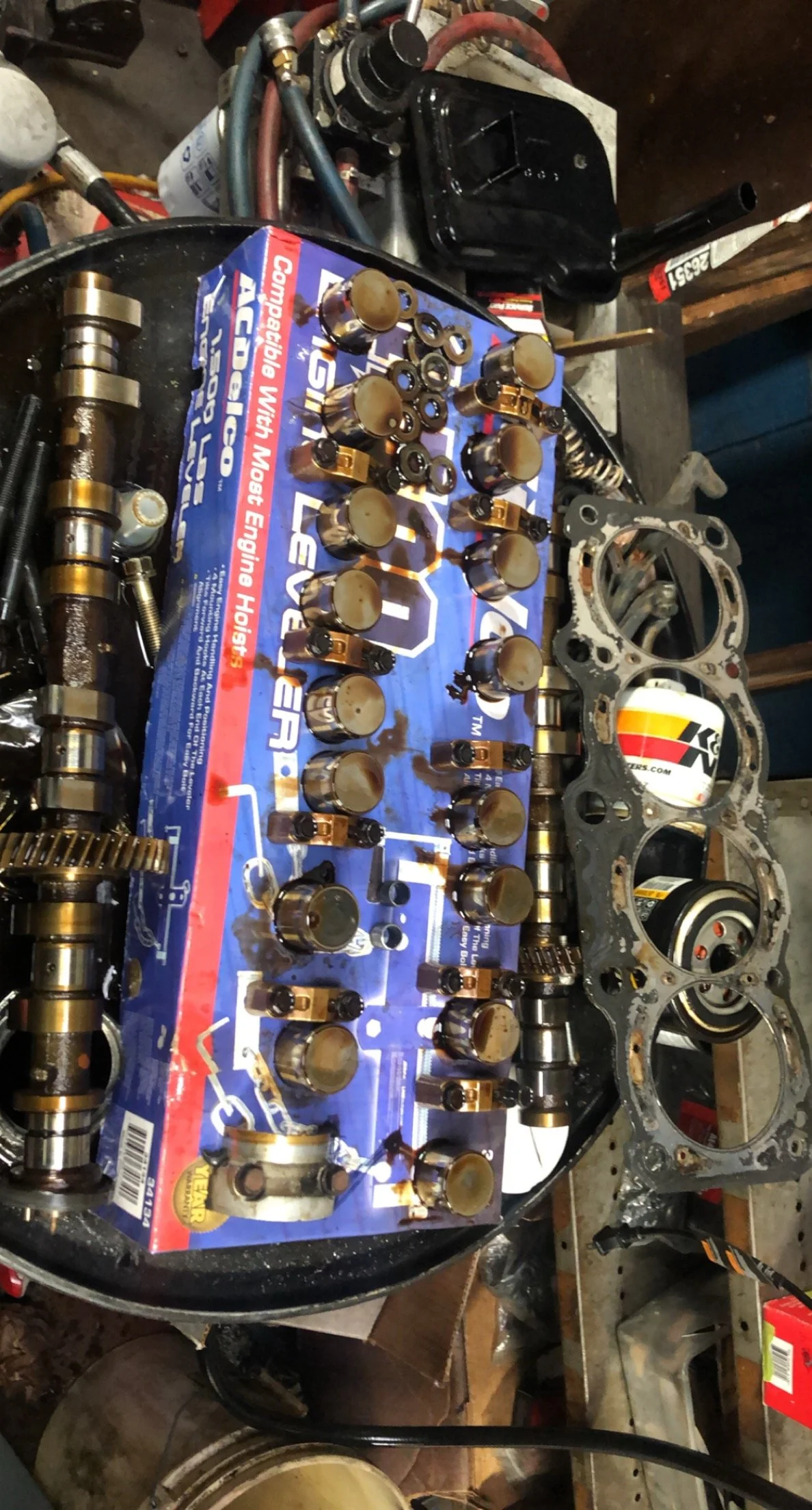 A disassembled car engine head with engine components and tools on a workbench.