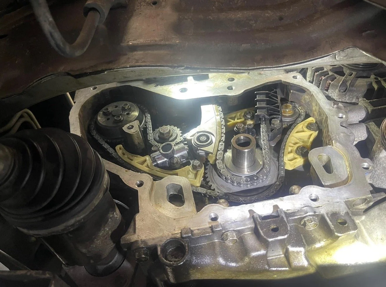 Interior view of a car engine with the valve cover removed, showing timing chain and related components.